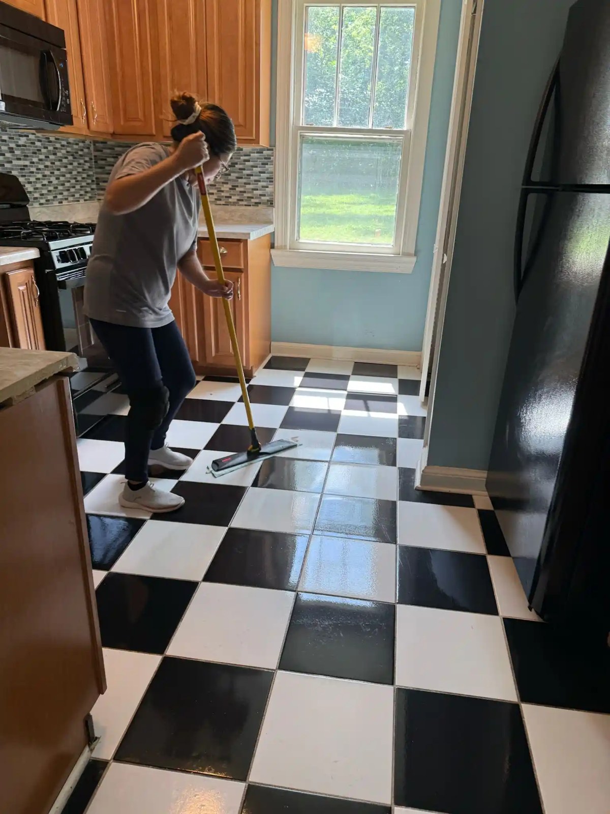 A cleaner mopping a checkered kitchen floor