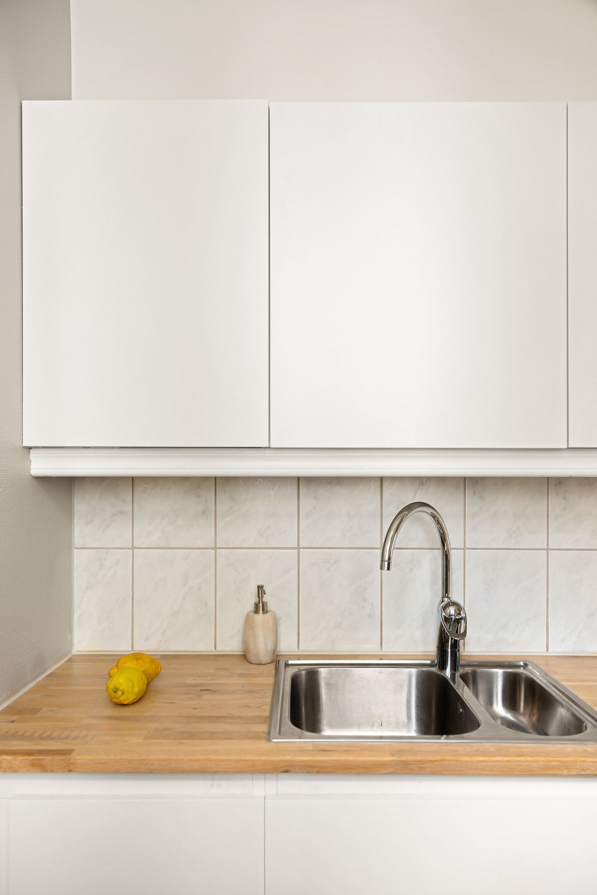 An elegant minimalist kitchen with white cabinets and a stainless steel sink