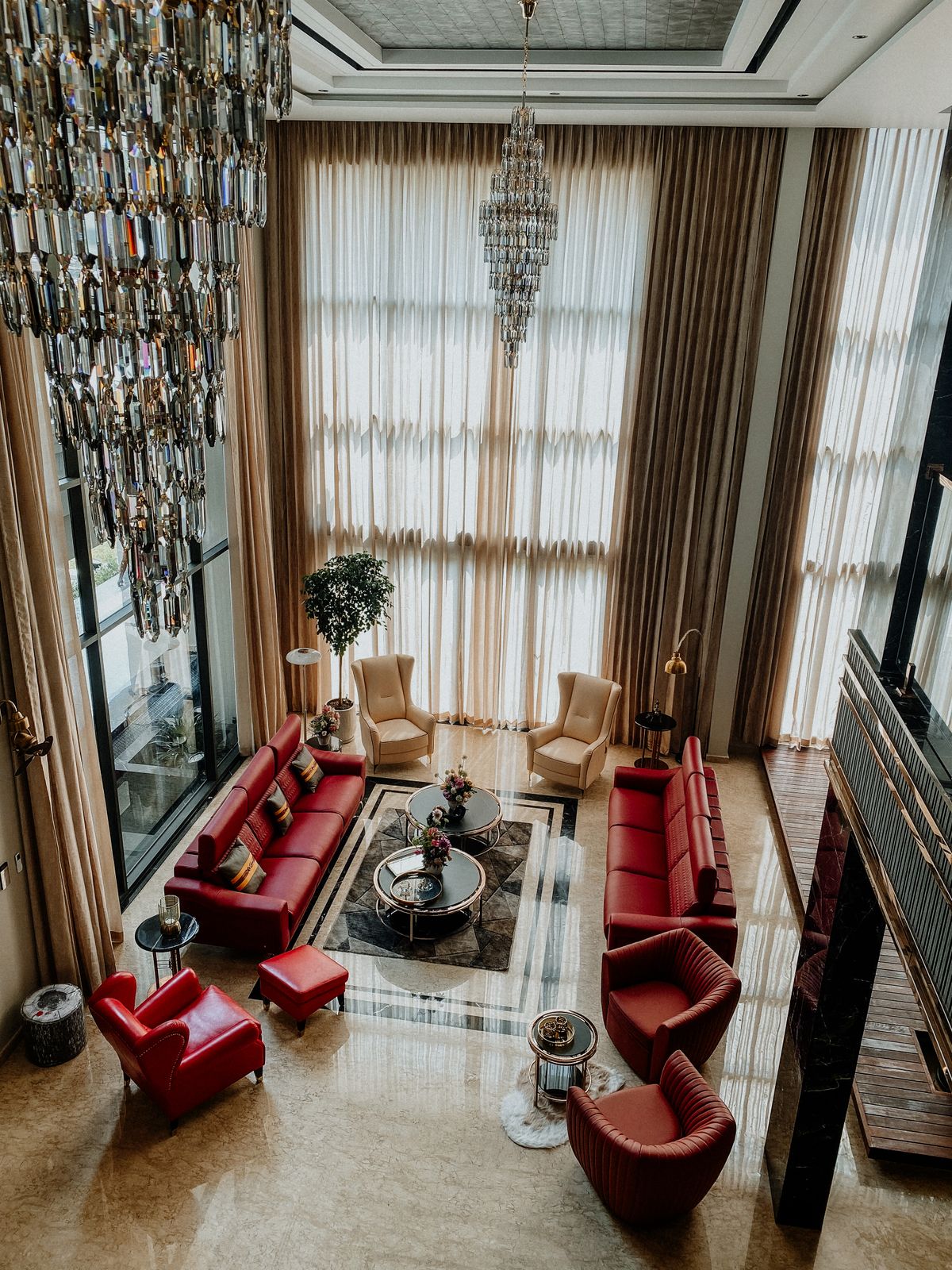A spacious living room with tall windows and red sofas