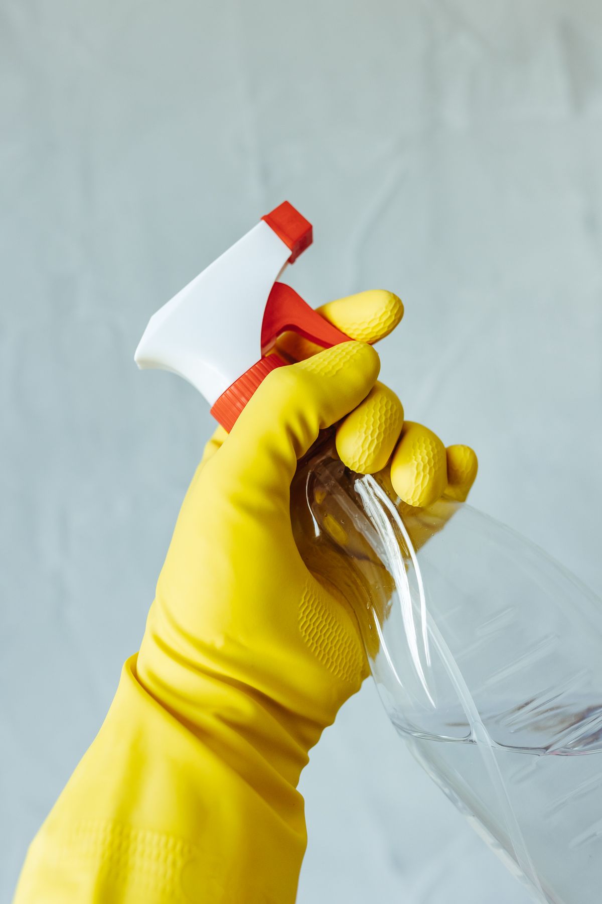 A gloved hand holding a spray bottle, ready to clean