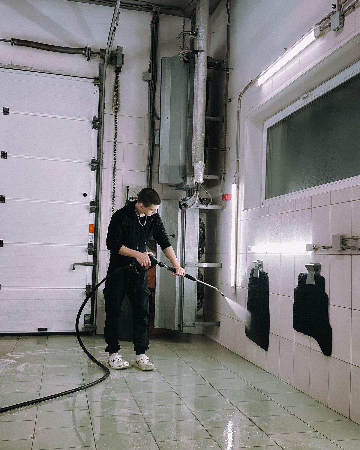 A worker pressure washing inside a wash bay
