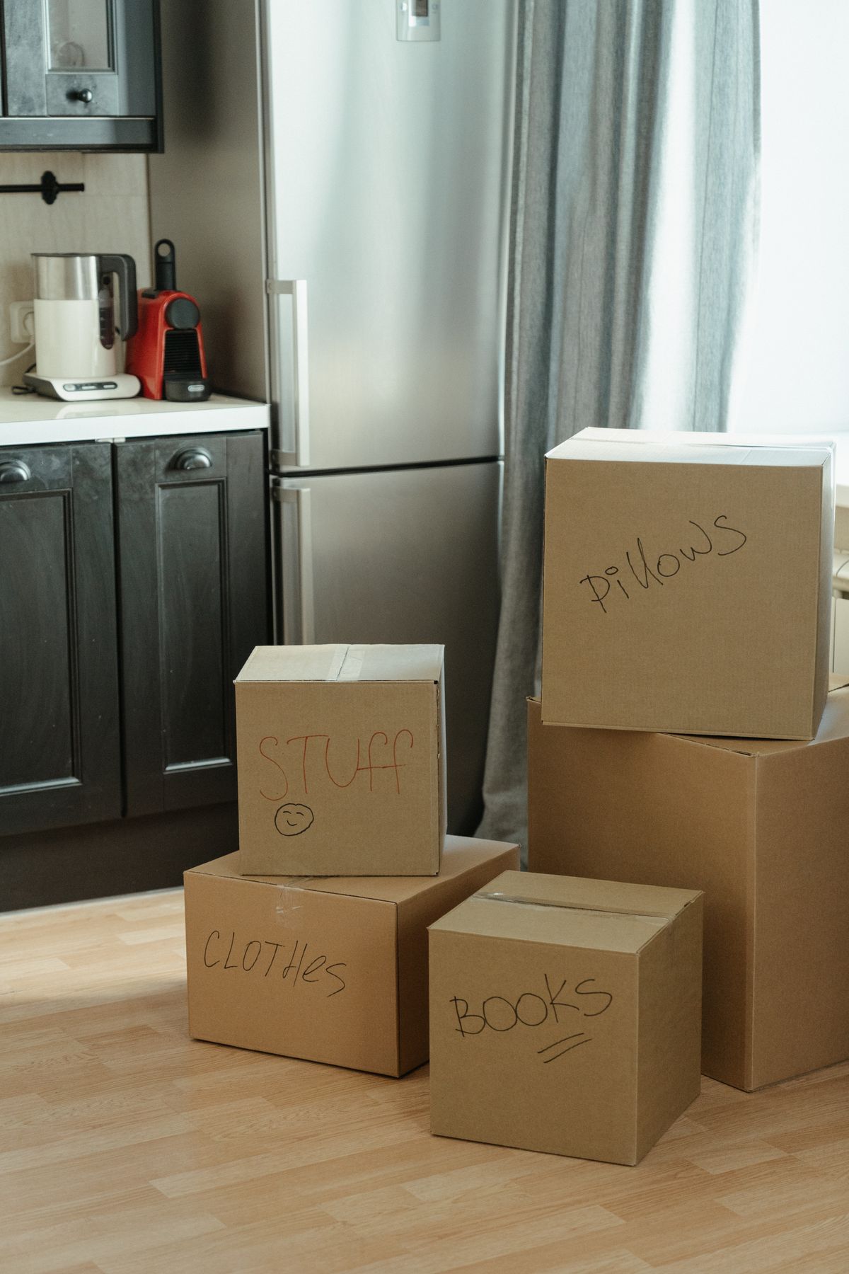 Cardboard moving boxes labeled with contents in a kitchen