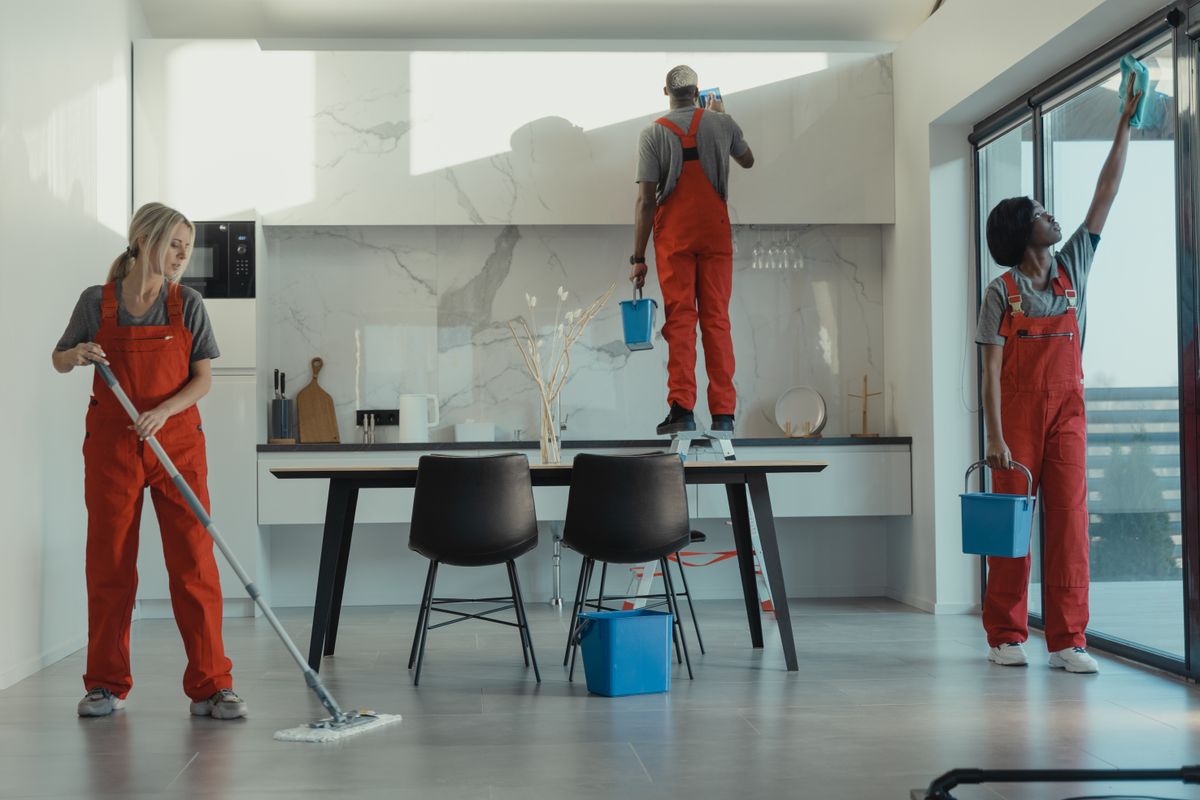 A cleaning team mopping and wiping glass in a modern workspace