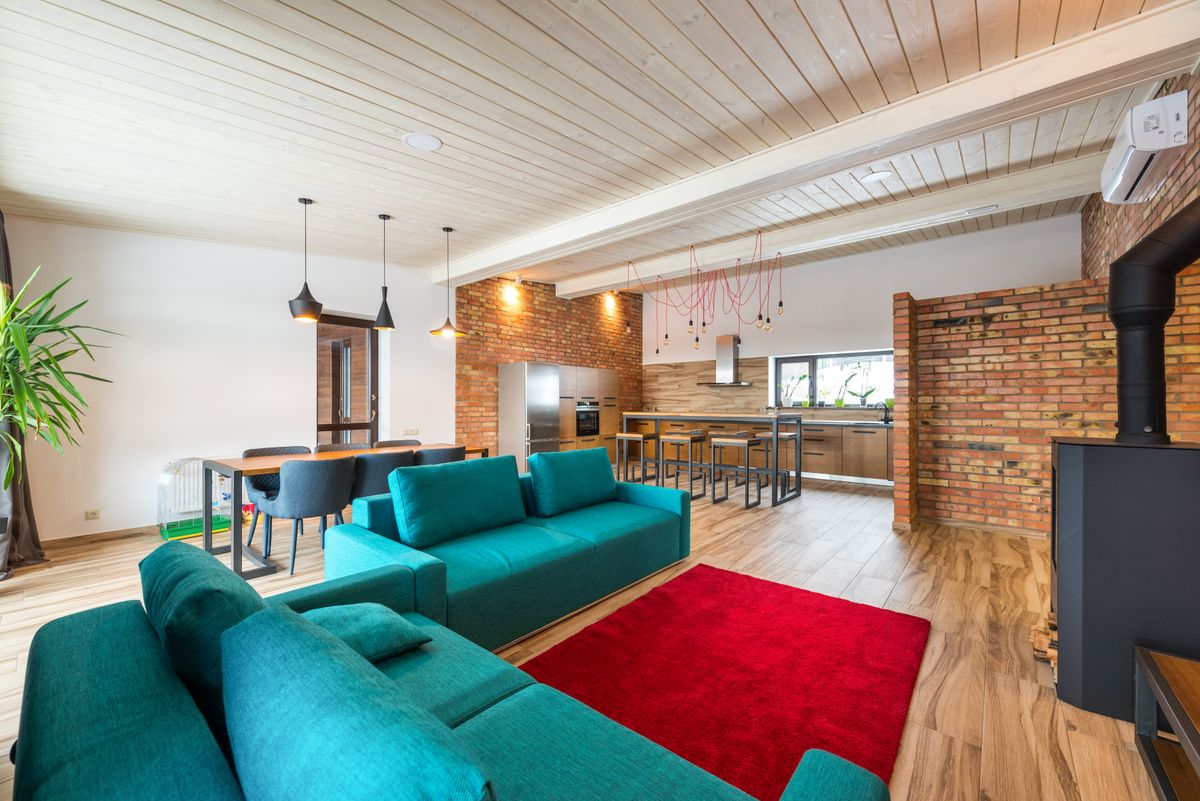 A bright open-plan apartment living space with a teal sofa